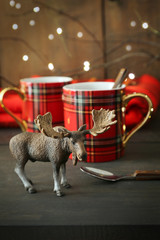 Small toy moose with mugs on rustic background