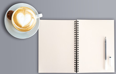top view of open spral note pad with blank pages and cup of cappuccino