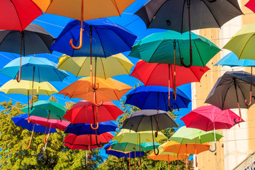 Obraz na płótnie Canvas Multicolored umbrellas on the city street. The city street is decorated with many colorful open umbrellas