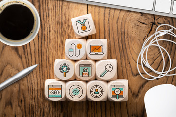 Online-Marketing Komponenten als Symbole auf Würfeln am Arbeitsplatz 