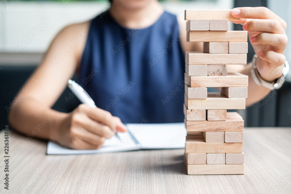 Wall mural businesswoman hand placing or pulling wooden block on the tower. business planning, risk management,