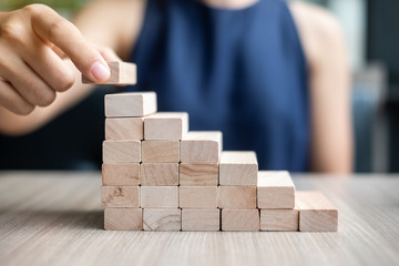 Businesswoman hand placing or pulling wooden block on the building. Business planning, Risk Management, Solution and strategy Concepts