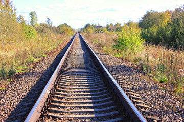 Fototapeta premium Podkłady kolejowe torów kolejowych na jesień krajobraz. Widok dworca kolejowego i kolejowego z perspektywy starych podkładów na tle obszarów wiejskich. Koncepcja transportu przemysłowego kolejowej drogi
