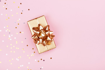 Golden gift or present box and stars confetti on pink background top view. Flat lay composition for...