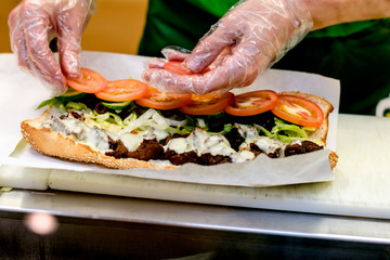 the seller at the fast food bar prepares a sandwich