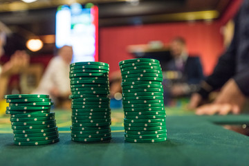 Casino, gambling and entertainment concept - stack of poker chips on a green table