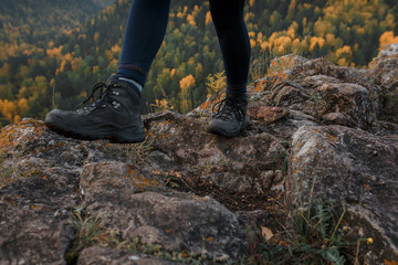 Close-up of legs in trekking boots on the background of autumn mountains