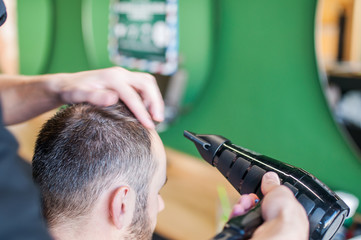 Barber man drying client's hair with hairdryer