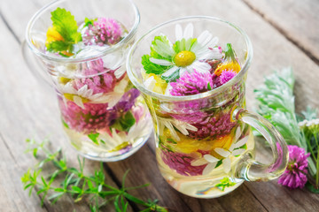 Two glass mugss of healthy herbal tea. Medicinal herbs on table.