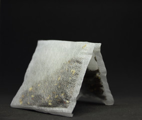 two square tea bags on a black background