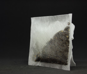 two square tea bags on a black background