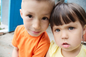 children selfie portraits sitting in front of home. Little girl and boy. Caucasian russian siblings together. Kids selfie together