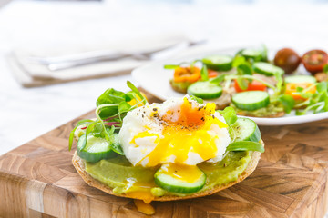 Raw healthy burger with avocado dressing, cucumbers, poached egg and multigrain bread. Superfood snack concept