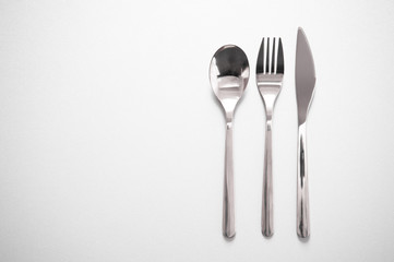 metal silverware of fork knife spoon for eating meal in restaurant grey background