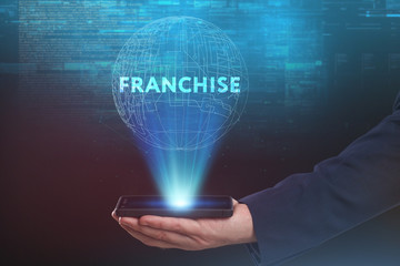 The concept of business, technology, the Internet and the network. A young entrepreneur working on a virtual screen of the future and sees the inscription: Franchise
