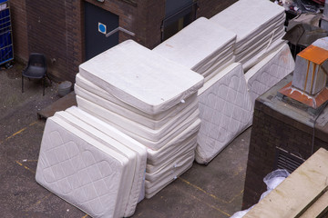 Stack of old and used mattresses left outside the back of a hotel while it is being re-furbished or to control a pest problem