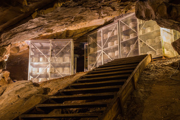 Large wheels of cheddar cheese on racks maturing or ageing inside a cave