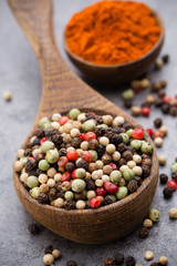 Peppercorn mix in a wooden bowl on grey table.