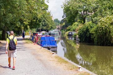 Avon and Somerset canal through Bath, England, with people walking on the towpath. Colourful barges...