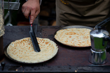 A man in an open-air picnic baked pancakes.