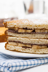 Fototapeta na wymiar sweet breakfast - sandwich with chocolate paste and banana, vertical closeup