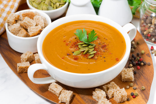 soup of pumpkin and lentils and ingredients on wooden board, closeup