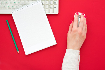 Obraz premium red Desk, woman hands, girl working at the computer, red background with copy space, for advertisement, top view