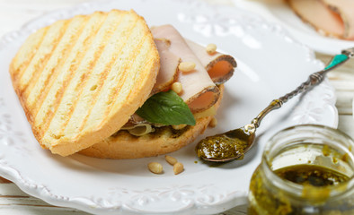 Delicious sandwich with baked ham, cheese, pesto sauce and pine nuts. Healthy snack for gourmets