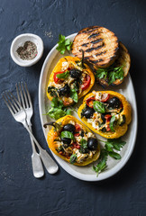 Baked bell peppers stuffed greek salad - delicious appetizers, snacks on a dark background, top view
