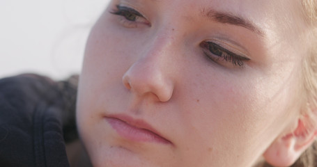 young female closeup portrait sitting on a seashore with thoughtful look