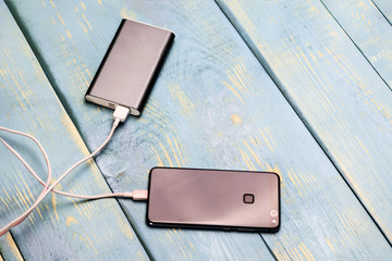 mobile phone and spare battery for charging on a wooden vintage background