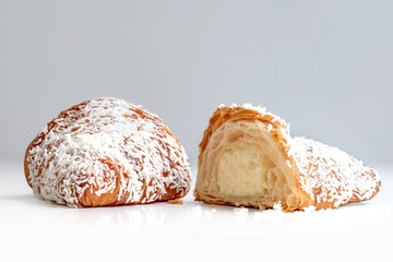 Freshly baked  croissant  cut in a half with coconut flakes  on white background close up