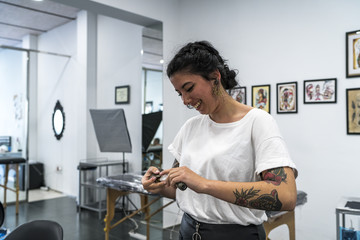 Fototapeta na wymiar Young woman tattooed preparing the tattoo machine.