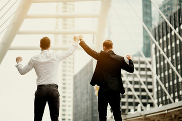 Portrait Caucasian Two businessmen standing behind, holding a hand of victory. In the big city This is because of teamwork with clear strategic planning. It makes the job a great success.