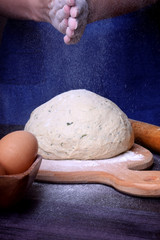 The baker is clapping hands covered with flour over the yeast dough