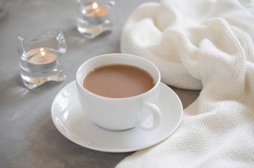 Cup of cocoa on a table, candles and knited blanket.