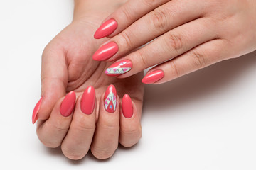 Coral, pink, orange manicure with crystals and a rhombus painted on long sharp nails on a white background close-up
