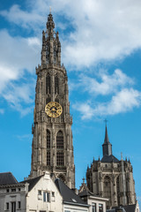 Fototapeta na wymiar Antwerp, Belgium - September 24, 2018: Closeup of Towers of Onze-Lieve-Vrouwe Cathedral of Our Lady in back under blue cloudy sky. Parts of white facades up front.