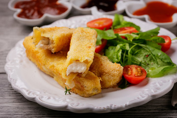 Fish sticks fried in breadcrumbs served with salad on a plate