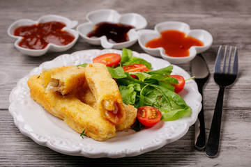 Fototapeta na wymiar Fish sticks fried in breadcrumbs with sauces