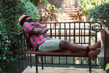 African traveller  sleeps at a bench in the park.