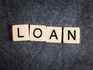 Letter tiles on black slate background spelling