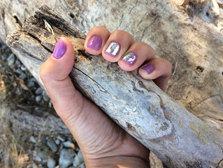 Female hand holding a branch of a tree. A sample of purple manicure. Beautiful well-groomed nails.