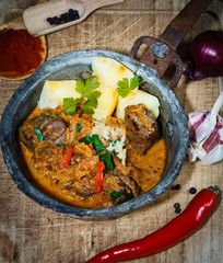 Alte Eisenpfanne auf altem Holzbrett mit Fleisch und Sauerkraut