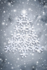 Decorative snowflakers laid in the form of a Christmas tree on a gray background.