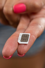Close - up of the SIM card lying on the girl's finger.