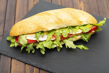 Baguette sandwich with ham, tomatoes, cheese and arugula lettuce. Delicious Breakfast or snack. Close up