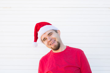Holidays, christmas and people concept - funny handsome man in santa hat have fun on white background