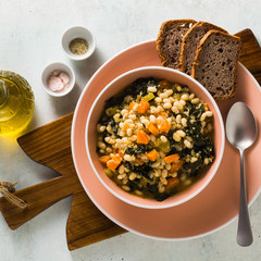 winter warming soup with kale and beans on the table with whole grain bread. healthy vegan food