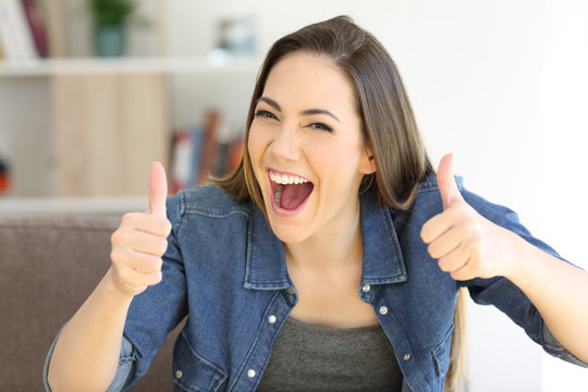 Excited woman with thumbs up at home